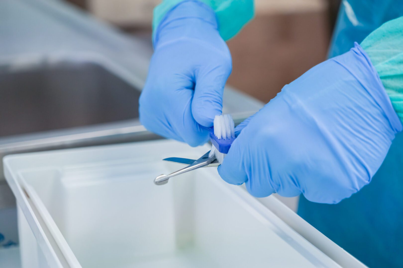 Gloved hands cleaning medical instruments.